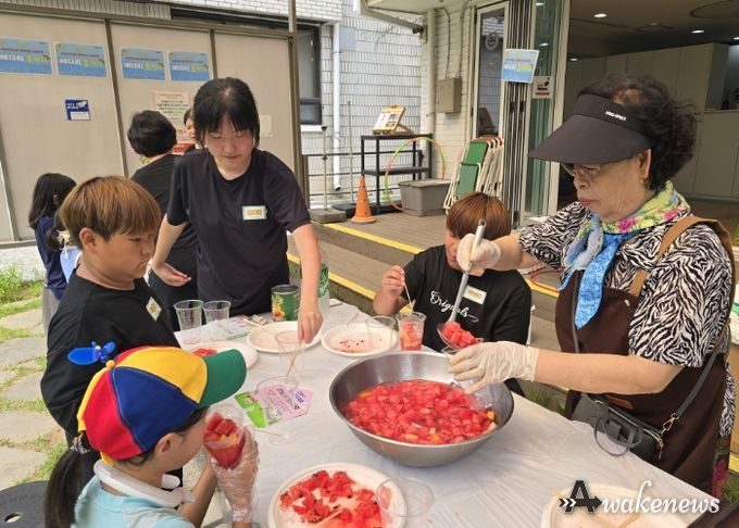 '우리마을 은빛 놀이터’프로그램에 참여한 어르신이 아이들에게 수박화채를 나눠주고 있다.