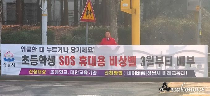 황금석 성남시의원이 초등학교 인근에 설치된 ‘초등학생 SOS 휴대용 비상벨’ 신청 안내 현수막 앞에 서 있다